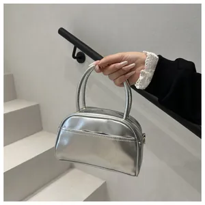 Detail view of a silver metallic semi-circle handbag featuring high-shine texture and dual handles