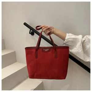 Dettaglio della borsa tote in pelle scamosciata rossa con logo e bordi in pelle