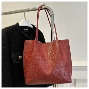 Macro view of dark red tote bag featuring woven texture and refined leather handles