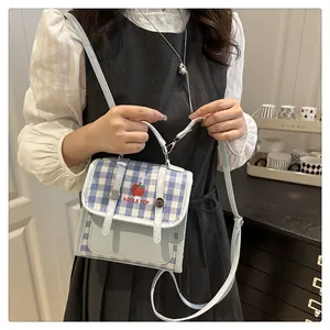 Close-up of blue gingham crossbody bag with red apple embroidery on a model
