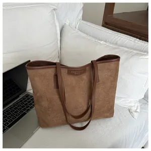 Dettaglio borsa tote in pelle scamosciata marrone con bordi in pelle su divano bianco