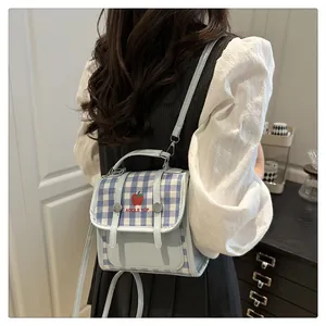Rear view of a model wearing the blue plaid crossbody bag with apple print detail