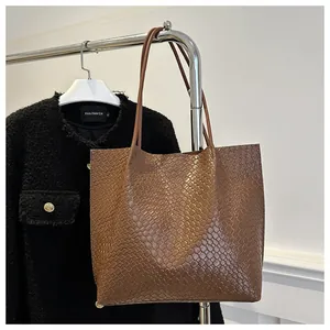 Close-up of brown woven texture leather tote bag hanging on a metal rack