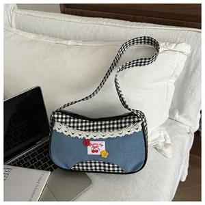 Detail of blue denim shoulder bag with lace trim and vintage cherry embroidery patch