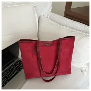 Dettaglio di una borsa tote grande in pelle scamosciata rossa con manici in pelle