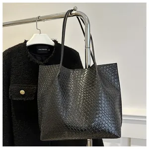 Macro detail of black woven leather texture on a minimalist commuter tote bag