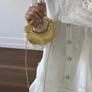 Detail of golden crescent handbag with ribbed texture and elegant snake chain strap
