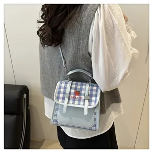 Detail of light blue gingham crossbody bag with apple print and buckle straps