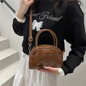 Retro glossy brown top-handle bag with adjustable strap and polished finish in a half-moon shape