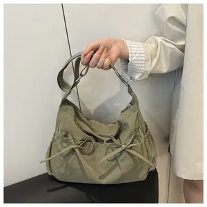 Detail of light olive green nylon shoulder bag with bow pockets and adjustable strap