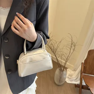 Minimalist white leather Boston handbag with top handles and front pocket for women