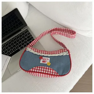 Detail of sweet blue denim bag with red check trim, cherry patch and lace lace decor