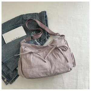 Macro view of light purple nylon shoulder bag featuring decorative drawstrings and bows