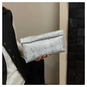 Detail of silver snake skin texture on an elegant folded clutch bag held by a model