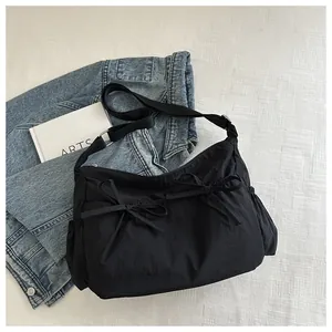 Close-up of black crossbody bag featuring dual bow details and adjustable nylon strap