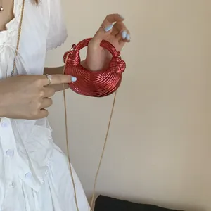 Close-up of bright red pleated mini bag with metal ring handle and gold chain strap