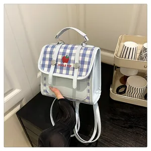 Detail of blue plaid backpack featuring red apple embroidery and double buckle closure