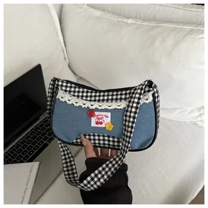 Detail of blue denim shoulder bag with lace trim, gingham patterns and cherry label
