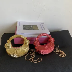Detail of metallic crescent mini bags with wave texture in gold and magenta colors