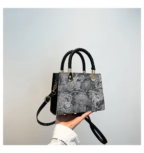 Dettaglio della trama jacquard floreale con finiture dorate e manico intrecciato nero