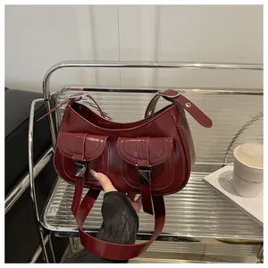 Detail of dark red glossy leather handbag featuring double front flap pockets with silver buckles