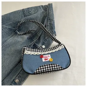 Detail of sweet blue denim handbag with plaid fabric, lace trim, and cherry embroidery