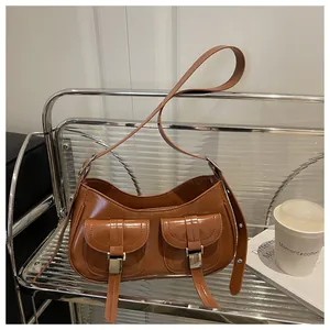 Detail of a brown glossy leather shoulder bag with two front pockets and silver buckles