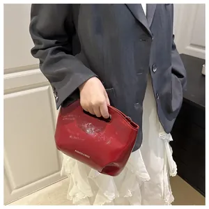 Detail of red glossy fashion handbag with cut-out handle and white lettering print