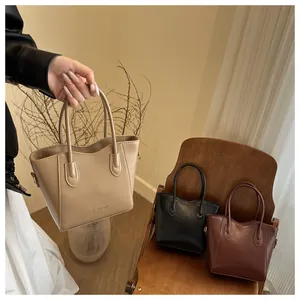 Close-up of minimalist bucket bags in beige, black and brown with debossed fashion text