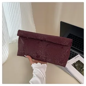 Macro view of burgundy snakeskin texture on a luxury fold-over clutch handbag