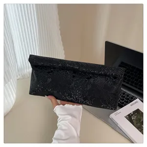 Detail of elegant black snakeskin textured clutch bag held in a professional setting