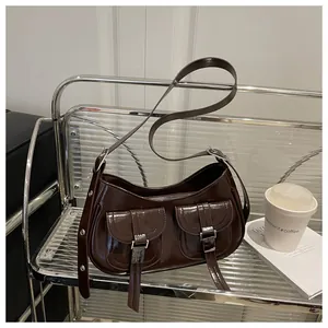 Detail of a dark brown patent leather shoulder bag with two pockets and silver buckles