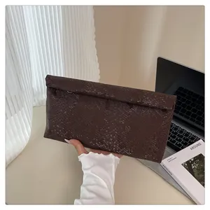 Detailed close-up of dark brown faux snake skin texture on flat rectangle clutch bag