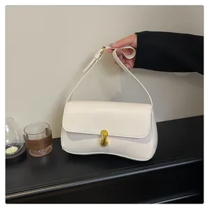 Detail of elegant ivory square handbag featuring a unique curved base and gold swivel lock