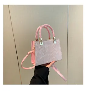 Détail du sac à main rose montrant le motif floral gaufré et les poignées tissées