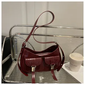 Detail view of burgundy leather handbag with dual front pockets and silver metal buckles