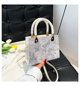 Dettaglio della borsa jacquard grigio argento con manico intrecciato e metallo dorato