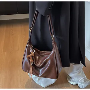 Bolso tote marrón retro con colgante de flecos y detalle de aro metálico en una modelo