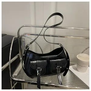 Macro detail of black glossy faux leather shoulder bag with two utility front pockets