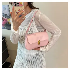 Detail of light pink shoulder bag with gold twist lock on white knit dress