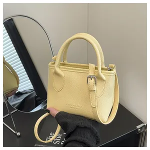 Detail of light yellow leather bucket bag with litchi texture and metal buckle accents