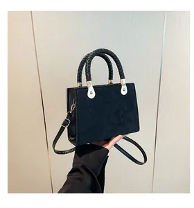 Détail du sac en similicuir noir gaufré avec poignées tressées et garnitures dorées