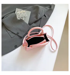 Dettaglio dell'interno di una borsa rosa in tessuto con scomparti e manico intrecciato