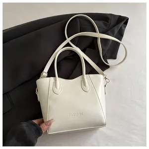 Close-up of cream leather bucket bag with FASHION embossed logo and gold hardware