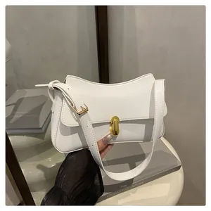Detail of white leather shoulder bag featuring a golden oval lock and sleek curved flap