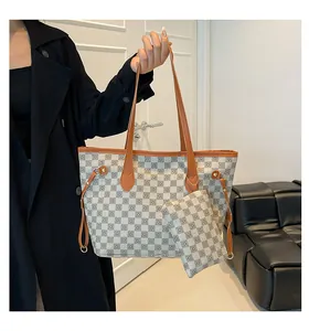 Dettaglio della borsa tote a scacchi con pochette coordinata e rifiniture in pelle marrone