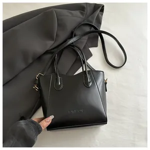 Detail of black bucket bag with FASHION embossing and gold hardware on blazer background