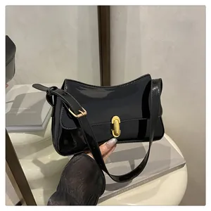 Detail of glossy black patent leather baguette bag with elegant golden oval metal lock