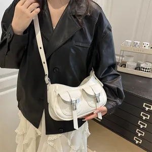 Chic white half-moon shoulder bag with dual front pockets and metal buckle details