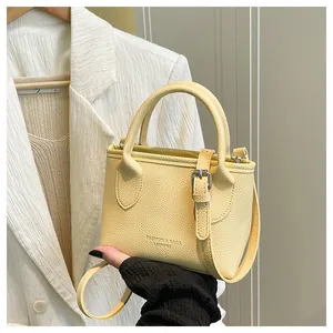 Detail of light yellow bucket bag with lychee grain texture and decorative buckle
